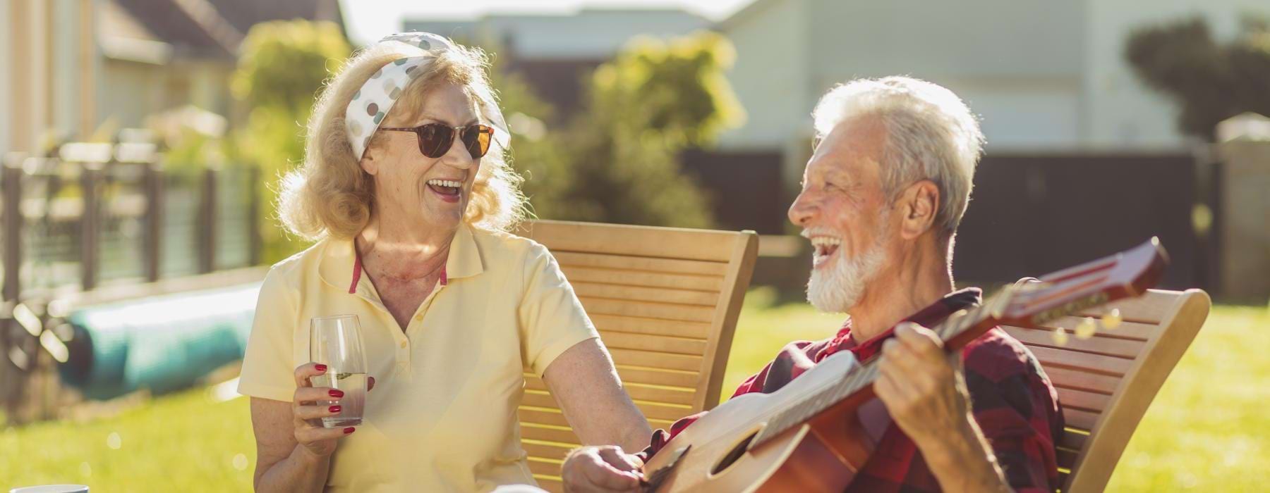 a man and woman sitting on a bench and playing guitar